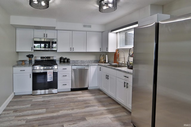5547 N W Shafer Dr, Monticello, IN 47960 - kitchen featuring appliances with stainless steel finishes, a sink, white cabinets, and light wood-style floors