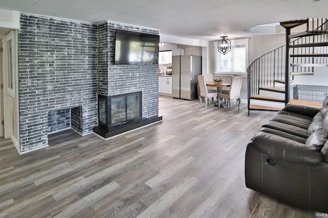 5547 N W Shafer Dr, Monticello, IN 47960 - living area featuring stairway, a tile fireplace, light wood finished floors, and a chandelier