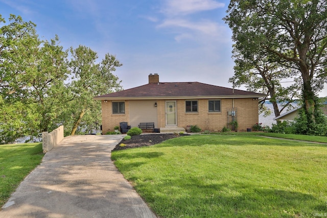 5547 N W Shafer Dr, Monticello, IN 47960 - view of front of house featuring a front yard, brick siding, a chimney, and driveway
