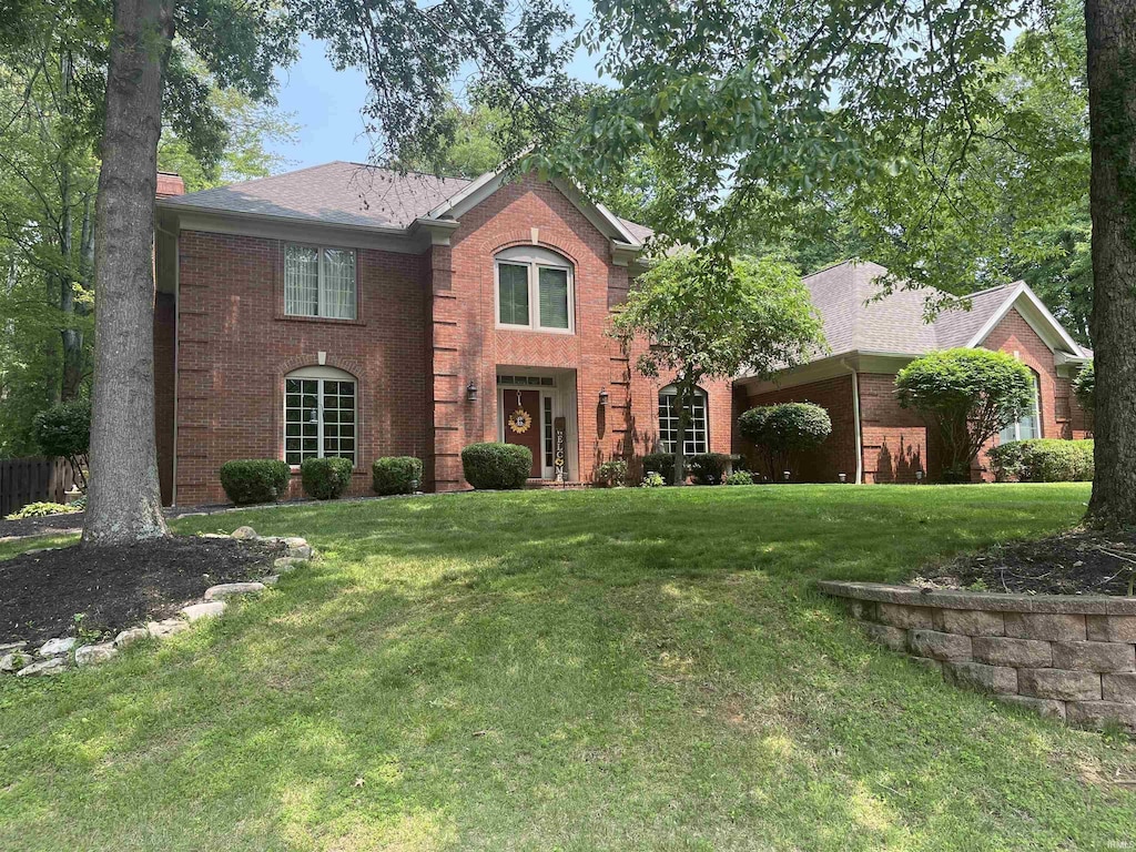 11621 German Pines Dr, Evansville, IN 47725 - colonial house featuring brick siding, a front lawn, and a chimney