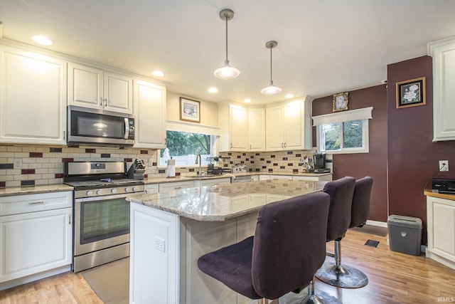 804 E Vistula St, Bristol, IN 46507 - kitchen featuring stainless steel appliances, a sink, white cabinets, light wood-type flooring, and tasteful backsplash
