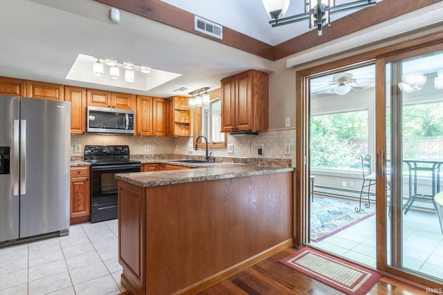 8816 Beacon Woods Pl, Fort Wayne, IN 46804 - kitchen featuring appliances with stainless steel finishes, a sink, a peninsula, brown cabinetry, and vaulted ceiling