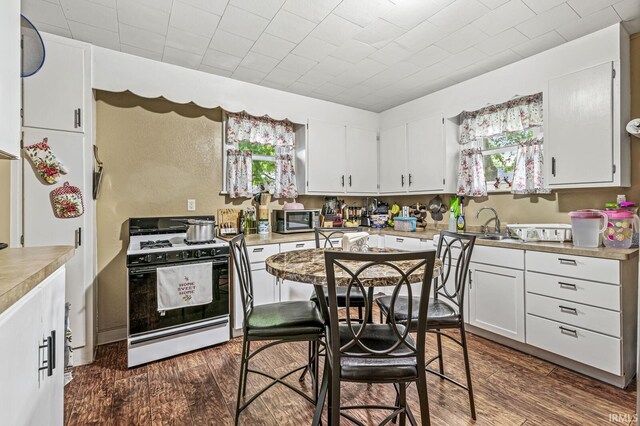 719 W Franklin St, Elkhart, IN 46516 - kitchen featuring gas range, stainless steel microwave, white cabinetry, and dark wood finished floors