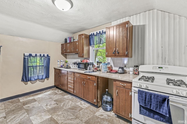 719 W Franklin St, Elkhart, IN 46516 - kitchen featuring white range with gas cooktop, lofted ceiling, stainless steel microwave, a textured ceiling, and light countertops