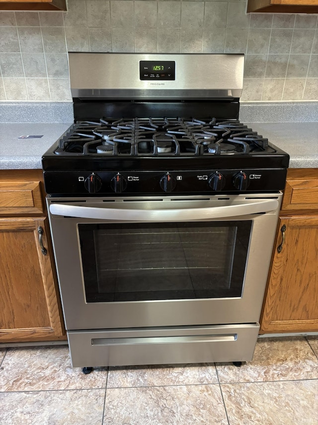 4026 S Lafayette St, Fort Wayne, IN 46806 - kitchen view of stainless steel gas range oven, brown cabinetry, backsplash, and light countertops