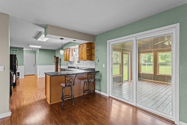 9391 E 100 N, Greentown, IN 46936 - kitchen with wood finished floors, a peninsula, open shelves, a kitchen breakfast bar, and dark countertops