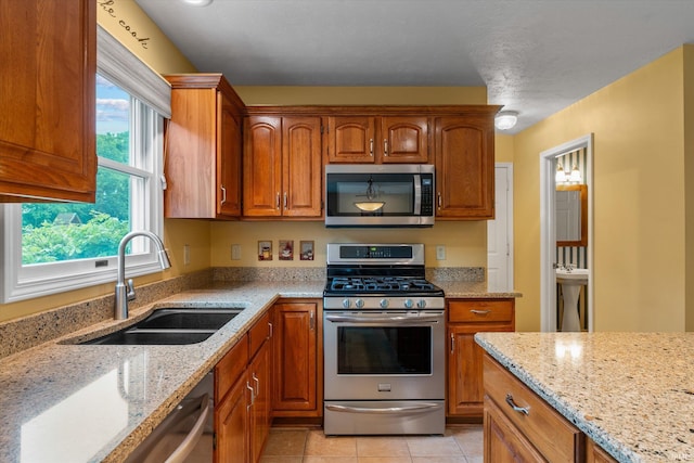 17813 Bromley Chase, South Bend, IN 46614 - kitchen with stainless steel appliances, a sink, brown cabinets, and light stone countertops