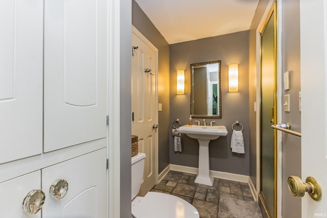 8804 W Tulip Tree Dr, Muncie, IN 47304 - bathroom with baseboards, stone tile flooring, toilet, and a sink