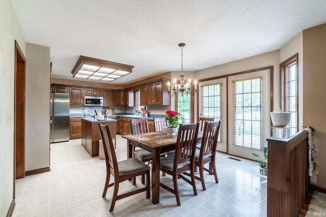 15329 Laurel Ridge Pl, Leo, IN 46765 - dining area featuring light flooring, a chandelier, baseboards, and a textured ceiling