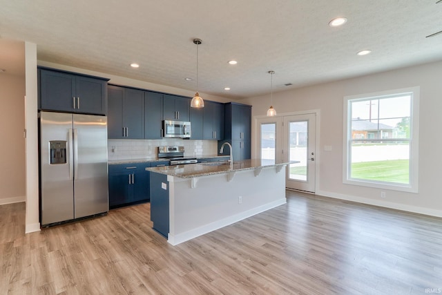 5708 Abbe Wood Dr, Newburgh, IN 47630 - kitchen featuring stainless steel appliances, light wood finished floors, an island with sink, a breakfast bar, and light stone countertops