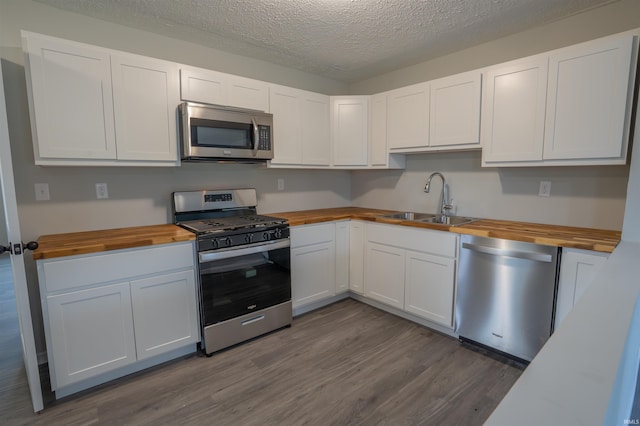 1109 E 6th St, Fowler, IN 47944 - kitchen with butcher block counters, stainless steel appliances, a sink, dark wood finished floors, and white cabinetry