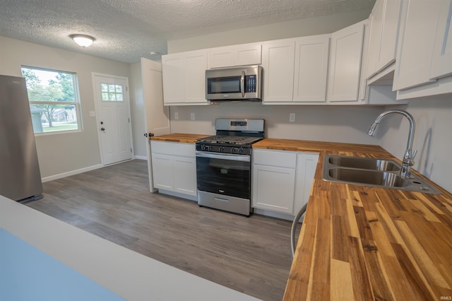 1109 E 6th St, Fowler, IN 47944 - kitchen with butcher block countertops, appliances with stainless steel finishes, a sink, dark wood-type flooring, and white cabinets