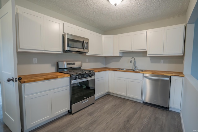 1109 E 6th St, Fowler, IN 47944 - kitchen featuring butcher block counters, stainless steel appliances, a sink, dark wood-style flooring, and a textured ceiling