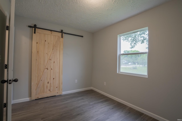 1109 E 6th St, Fowler, IN 47944 - spare room featuring dark wood-style floors, a barn door, baseboards, and a textured ceiling