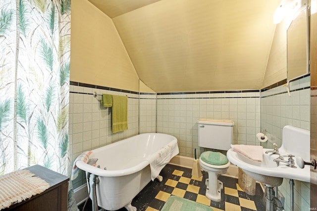 1202 S Van Buren St, Auburn, IN 46706 - full bath with tile patterned floors, vaulted ceiling, a freestanding bath, tile walls, and a wainscoted wall