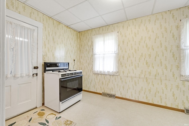 1202 S Van Buren St, Auburn, IN 46706 - kitchen featuring white gas stove, a paneled ceiling, light colored carpet, wallpapered walls, and baseboards