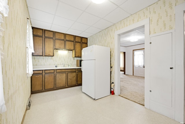 1202 S Van Buren St, Auburn, IN 46706 - kitchen with freestanding refrigerator, wallpapered walls, a drop ceiling, light countertops, and brown cabinets