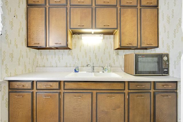 1202 S Van Buren St, Auburn, IN 46706 - kitchen featuring wallpapered walls, black microwave, a sink, light countertops, and brown cabinetry