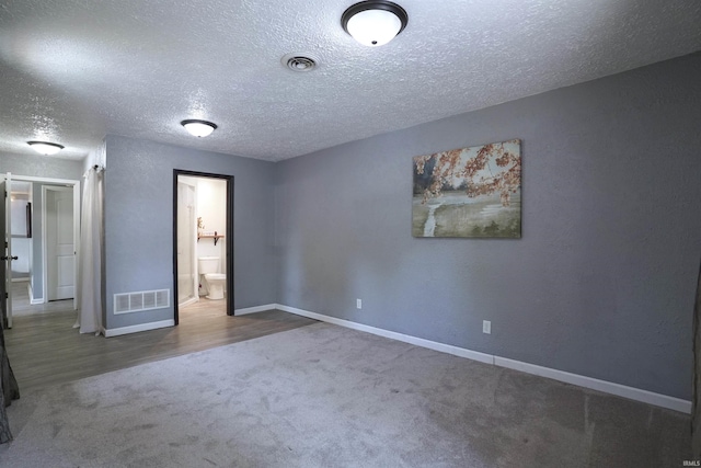 52589 Lilac Rd, South Bend, IN 46628 - unfurnished bedroom featuring carpet floors, a textured ceiling, baseboards, ensuite bathroom, and wood finished floors