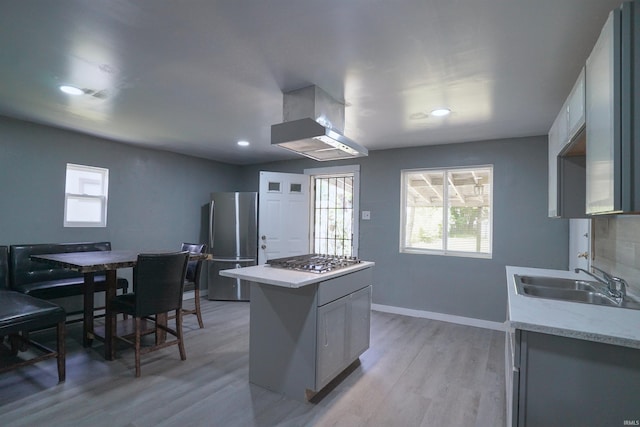 2117 Linden Ave, South Bend, IN 46628 - kitchen with stainless steel appliances, wall chimney exhaust hood, a sink, light countertops, and light wood-style floors