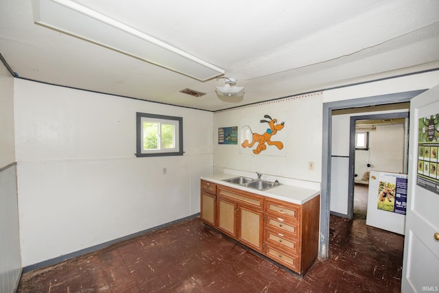 121 W Vine St, Delphi, IN 46923 - kitchen featuring a sink, brown cabinetry, light countertops, dark flooring, and baseboards