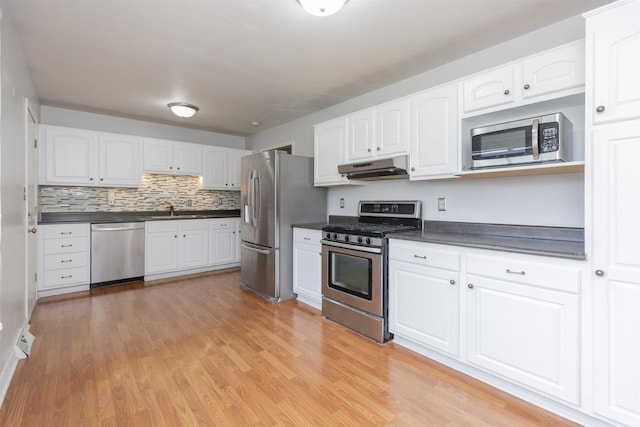 53140 Bowercrest Ct, South Bend, IN 46635 - kitchen with appliances with stainless steel finishes, dark countertops, under cabinet range hood, and light wood-style flooring
