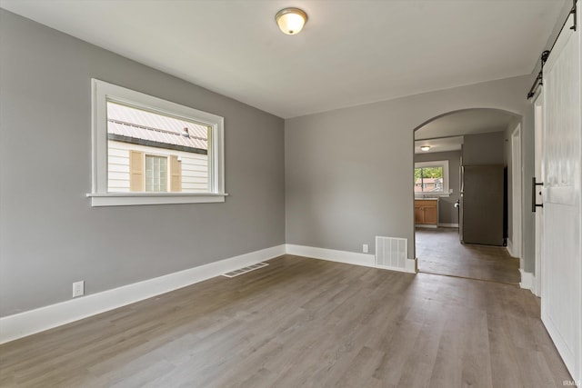 1815 E Bowman St, South Bend, IN 46613 - empty room with arched walkways, a barn door, light wood finished floors, and baseboards