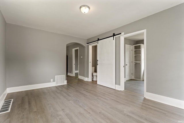 1815 E Bowman St, South Bend, IN 46613 - unfurnished room with arched walkways, light wood-style floors, baseboards, and a barn door