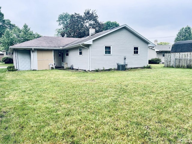 121 N Oakley Ave, Mishawaka, IN 46544 - back of property with a lawn, an attached garage, a shingled roof, and a chimney