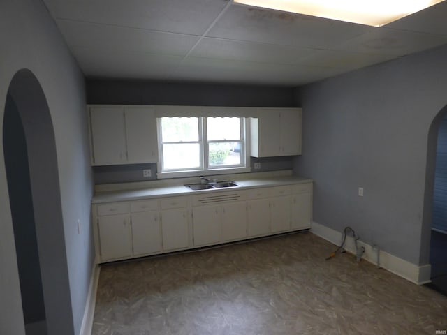 302 W Freeman St, Frankfort, IN 46041 - kitchen featuring arched walkways, light countertops, white cabinets, and a sink