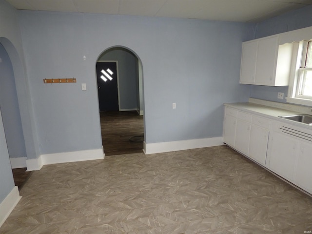 302 W Freeman St, Frankfort, IN 46041 - kitchen featuring arched walkways, a sink, white cabinets, and light countertops