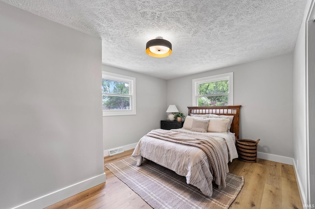 5012 Autumn Ln, Lafayette, IN 47909 - bedroom featuring baseboards, multiple windows, light wood finished floors, and a textured ceiling