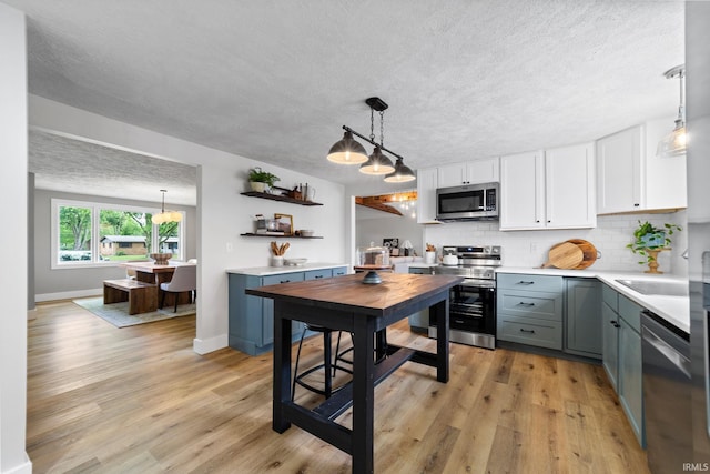 5012 Autumn Ln, Lafayette, IN 47909 - kitchen with appliances with stainless steel finishes, tasteful backsplash, light countertops, white cabinetry, and pendant lighting