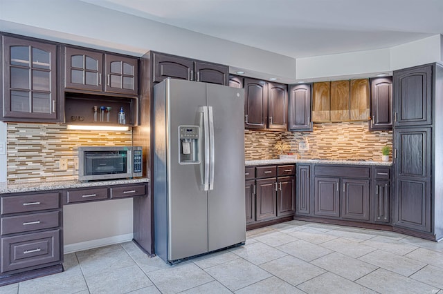 505 Wyndclyff Dr, Evansville, IN 47711 - kitchen with appliances with stainless steel finishes, light tile patterned floors, backsplash, glass insert cabinets, and dark brown cabinetry