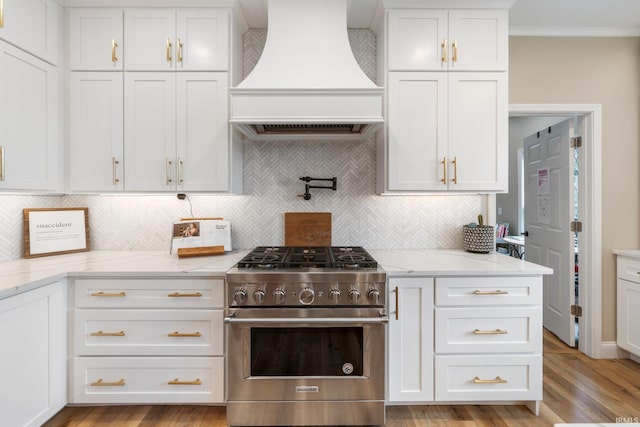 14609 Carrigan Ct, Granger, IN 46530 - kitchen with stainless steel stove, custom range hood, white cabinets, backsplash, and crown molding