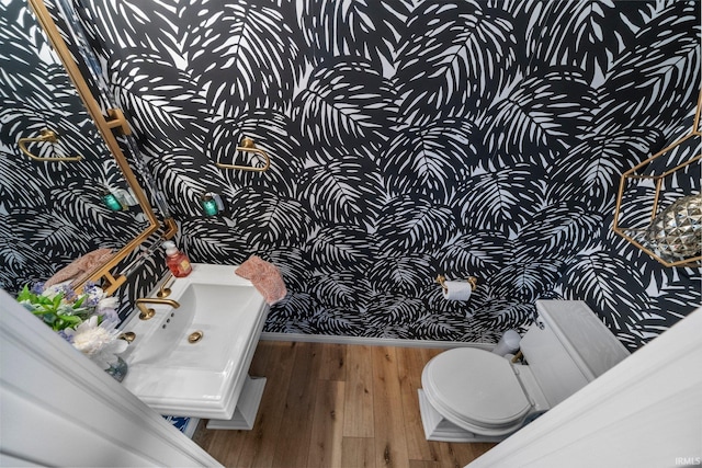 14609 Carrigan Ct, Granger, IN 46530 - bathroom featuring wallpapered walls, wood finished floors, toilet, and baseboards