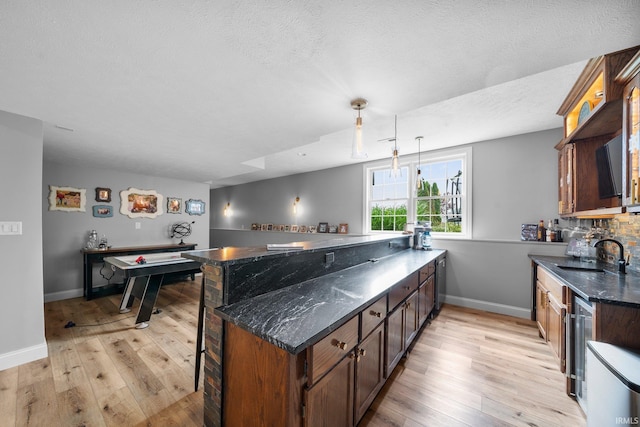 14609 Carrigan Ct, Granger, IN 46530 - kitchen with a sink, light wood-type flooring, dark stone counters, baseboards, and a textured ceiling