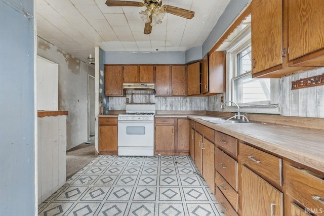 1008 E Spraker St, Kokomo, IN 46901 - kitchen featuring white gas range, a sink, under cabinet range hood, brown cabinetry, and light countertops