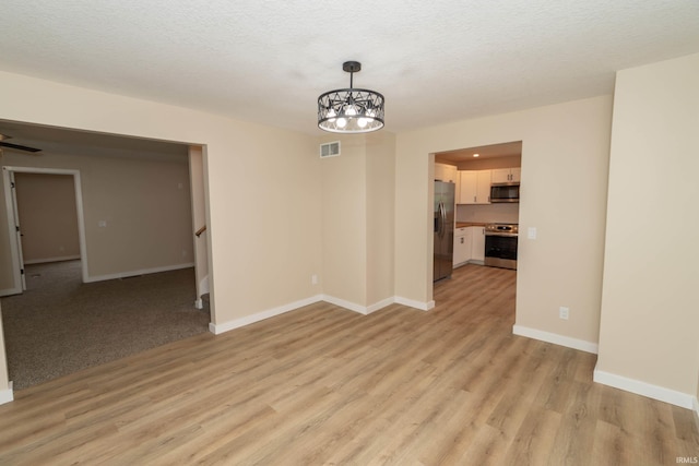 400 E Center St, North Liberty, IN 46554 - unfurnished room with light wood-type flooring, baseboards, a chandelier, and a textured ceiling