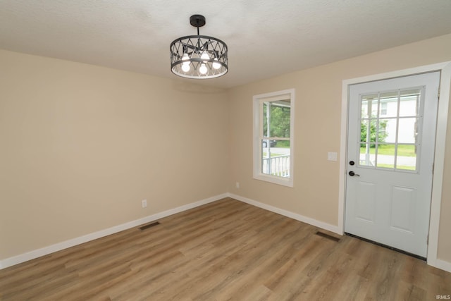 400 E Center St, North Liberty, IN 46554 - unfurnished dining area with a chandelier, light wood-style flooring, baseboards, and a textured ceiling