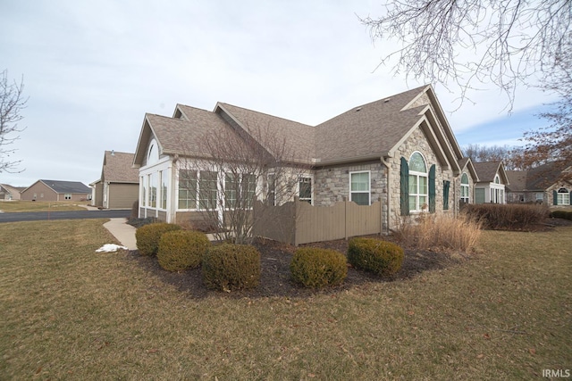 4654 Ironstone Ln, West Lafayette, IN 47906 - view of side of property featuring stone siding, roof with shingles, a yard, a garage, and asphalt driveway