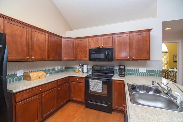 4654 Ironstone Ln, West Lafayette, IN 47906 - kitchen with black appliances, vaulted ceiling, a sink, light wood finished floors, and light countertops