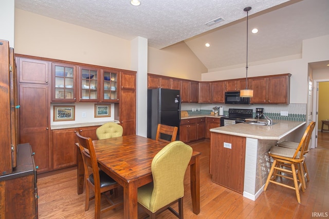 4654 Ironstone Ln, West Lafayette, IN 47906 - kitchen featuring black appliances, a peninsula, vaulted ceiling, a textured ceiling, and light wood-style flooring