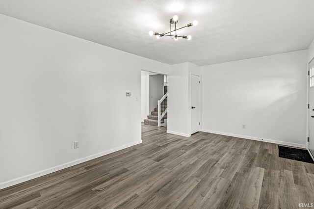 57372 Arabian Dr, Goshen, IN 46528 - empty room featuring a chandelier, dark wood-style flooring, baseboards, and stairs