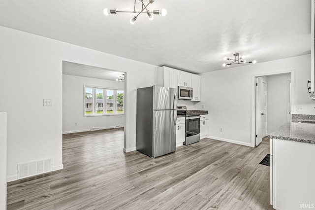 57372 Arabian Dr, Goshen, IN 46528 - kitchen with appliances with stainless steel finishes, a chandelier, light stone countertops, white cabinets, and light wood-style flooring