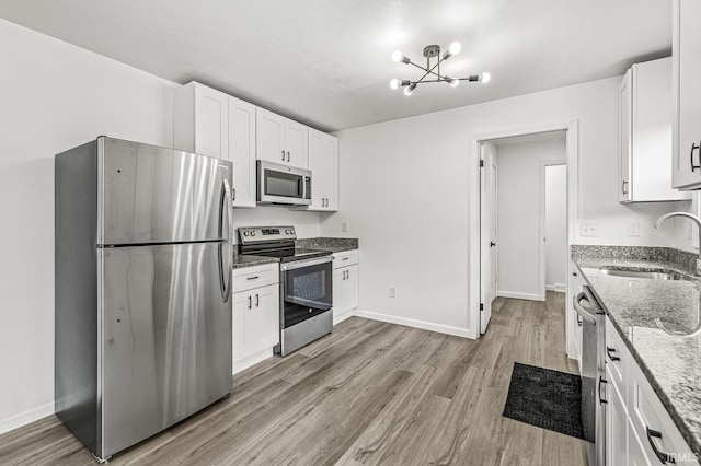 57372 Arabian Dr, Goshen, IN 46528 - kitchen featuring stainless steel appliances, a sink, light stone counters, and light wood-style flooring