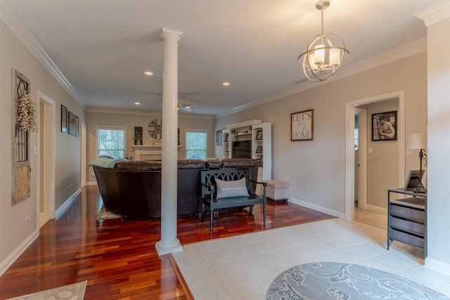 2534 Wheaton Dr, Evansville, IN 47725 - foyer entrance featuring light wood-type flooring, ornate columns, a chandelier, ornamental molding, and a fireplace