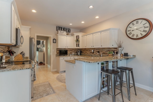 2534 Wheaton Dr, Evansville, IN 47725 - kitchen featuring a peninsula, a kitchen breakfast bar, stainless steel appliances, tasteful backsplash, and recessed lighting