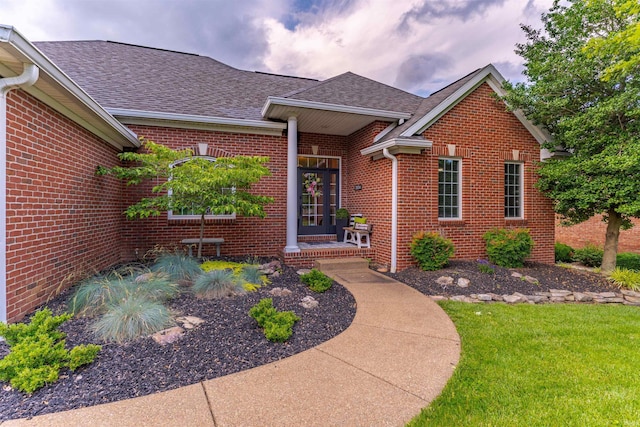 2534 Wheaton Dr, Evansville, IN 47725 - view of exterior entry featuring brick siding, roof with shingles, and a lawn
