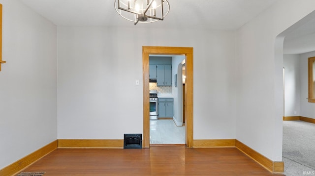 4112 Arlington Ave, Fort Wayne, IN 46807 - unfurnished room with a chandelier, baseboards, wood finished floors, and arched walkways